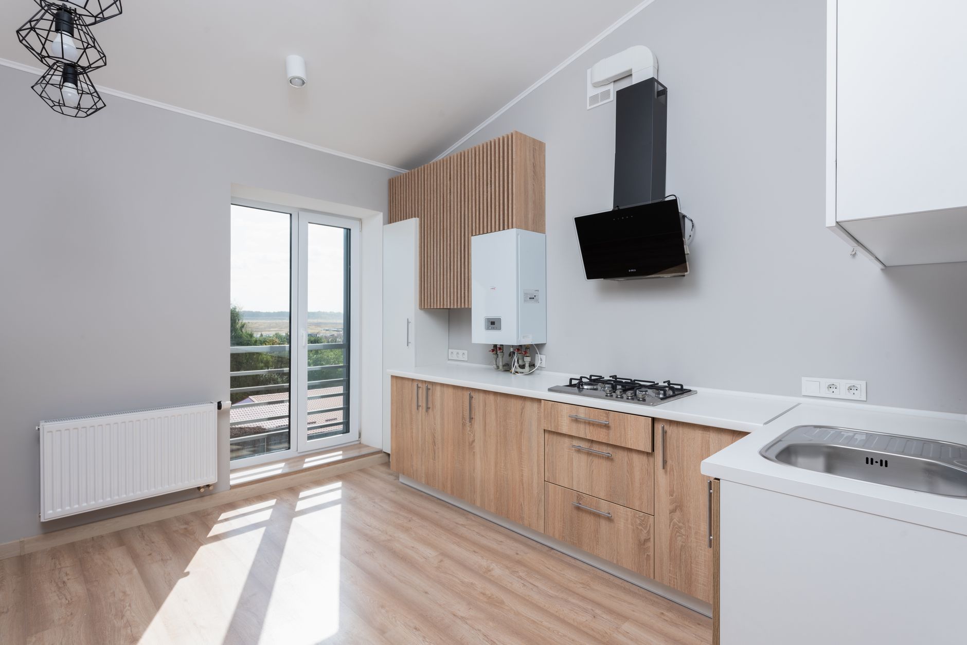 Stylish empty kitchen with wooden cabinets and large windows. — Risks of Asbestos in Attic Insulation