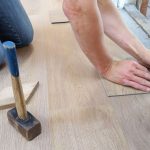 A craftsman carefully measures and marks wooden floor panels for precise installation. — Vavada kasiinosse sisselogimise meet