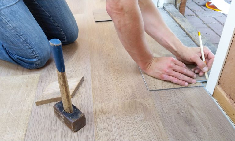 A craftsman carefully measures and marks wooden floor panels for precise installation. — Vavada kasiinosse sisselogimise meet